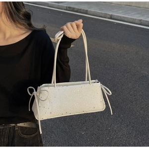 Détail du sac baguette blanc avec imprimés étoiles argentées et ruban élégant sur le côté