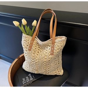 Close-up of straw tote bag with brown leather handles and white tulip decor