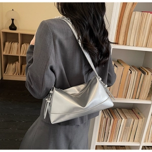 Detail of silver shoulder bag with long tassels shown on a model in a library