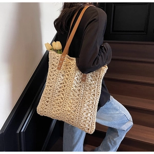 Detail view of woven straw tote bag with brown leather straps and tulip decor