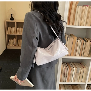 Detail of light purple glossy patent leather underarm tote bag worn with grey blazer