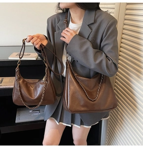 Detail of vintage dark brown leather tote and shoulder bag with gold chain strap
