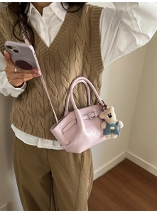 Close-up of pink bucket bag with adjustable strap and cute teddy bear plush charm