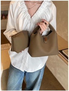 Détail d'un sac seau marron à motif litchi avec fermoir doré et pochette assortie