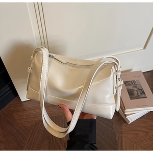 Detail view of the cream-colored smooth leather texture and adjustable shoulder strap buckle