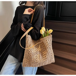 Detail of woven straw tote bag with brown leather shoulder straps and tulip decor