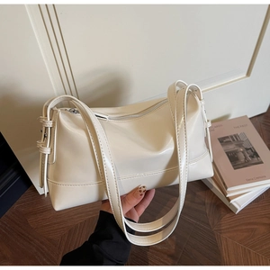 Detail view of cream white PU leather tote bag with smooth texture and metal zipper closure