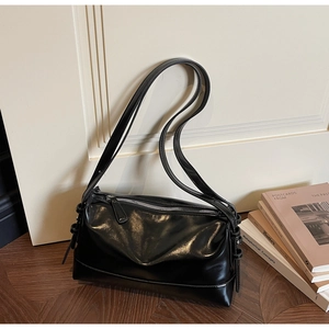 Detailed macro view of black glossy patent leather shoulder bag with silver metal zipper