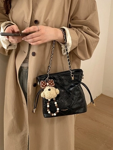 Quilted black bucket bag with chain strap and cute plush dog pendant for daily commute