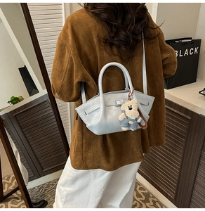 Detailed back view of a light blue crossbody bucket bag with a cute bear charm accessory