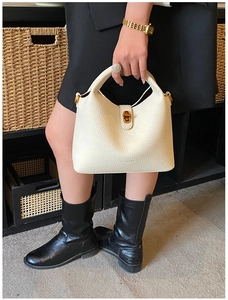 Détail du sac seau crème montrant le cuir grainé et le fermoir pivotant doré chic