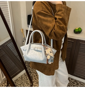Close-up of light blue leather bucket bag with a cute denim teddy bear charm detail