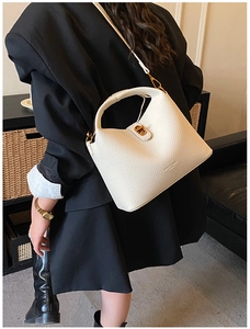 Détail d'un sac seau en cuir blanc crème avec ferrures dorées et texture grainée