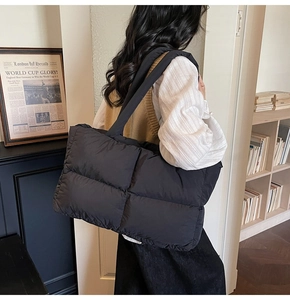 Close-up of black quilted puffer tote bag featuring oversized square stitching patterns