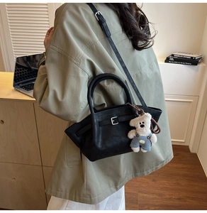 Detail of black bucket bag with silver hardware and a cute white bear plush charm on side