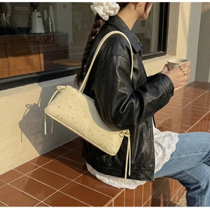 Détail d'un sac baguette crème avec motifs étoiles dorées dans un décor de rue chic