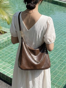 Vintage dark brown large tote bag with gold chain strap on woman in summer dress