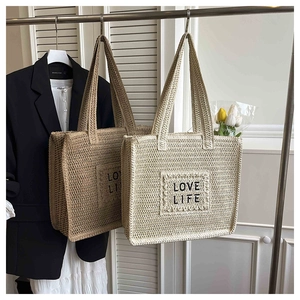 Détails rapprochés de cabas en paille tressée avec texte LOVE LIFE brodé et larges poignées