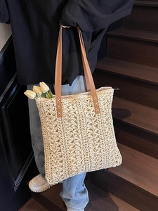 Minimalist straw tote bag with brown leather straps and woven pattern for beach style