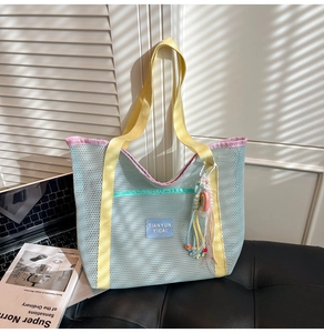 Détail du cabas en mesh bleu avec anses jaunes et bordure rose sur fond de cuir noir