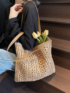 Minimalist straw tote bag with brown leather handles and decorative flowers for beach use