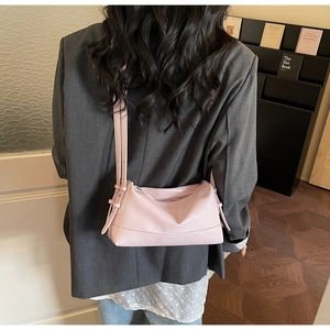 Pink minimalist faux leather shoulder bag worn by a model in a professional office setting