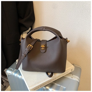 Vue détaillée du cuir grainé marron foncé et du fermoir rotatif doré du sac seau chic