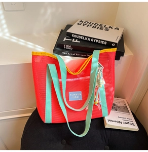 Détail du sac cabas en maille rouge avec liseré contrasté et breloque en perles