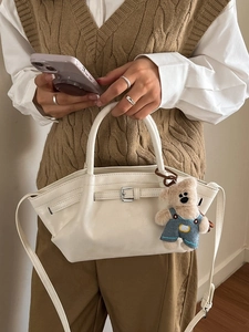 Fashionable cream white PU bucket bag with cute bear pendant worn as crossbody by model