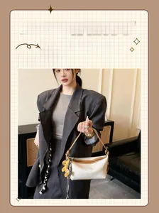 Détail du sac bandoulière en cuir contrasté avec breloque animale jaune et accents métal