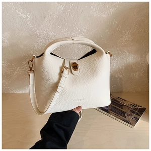 Détail du sac seau en cuir grainé avec fermoir doré et une bandoulière réglable