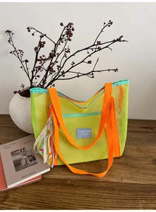Détail du sac cabas en maille contrastée avec poignées orange et breloque bohème