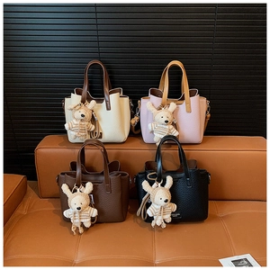 Detail view of four textured leather tote bags in various colors with cute plush bunny charms
