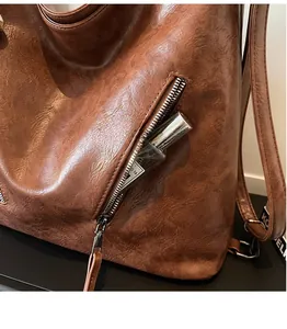 Detail of vintage brown leather bag showing the side zipper pocket and storage capacity