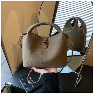Détail du sac seau en cuir taupe grainé avec fermoir rotatif en métal doré élégant