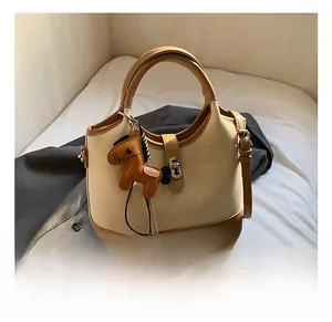 Detail view of two-tone bucket bag with metal buckle and decorative horse charm