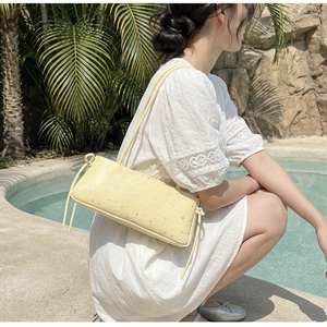 Sac baguette jaune pâle à paillettes étoiles argentées dans un décor estival au bord de l'eau