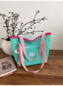 Détail du sac cabas en maille vert menthe avec anses roses et breloque arc-en-ciel