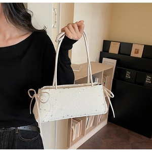 Vue détaillée du sac baguette blanc avec imprimés étoiles argentées et nœuds décoratifs