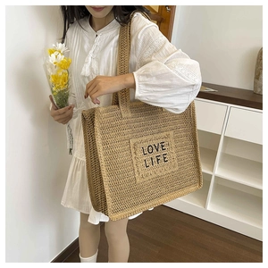 Détail d'un cabas en paille tressée avec broderie LOVE LIFE pour un look estival