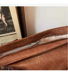 Close-up detail of smooth silver metal zipper on vintage brown leather shoulder bag