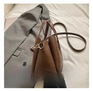 Detailed macro view of silver metal D-ring hardware on brown lychee grain leather handbag