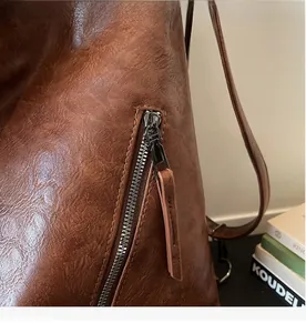 Close-up of the durable metal zipper and brown textured leather pull on the retro bag