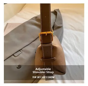 Détail d'un sac bandoulière en cuir marron avec bandoulière réglable et boucle en métal doré