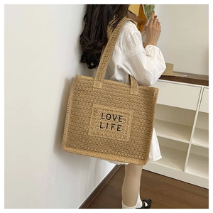 Détail de la broderie LOVE LIFE sur un grand sac fourre-tout en paille tressée