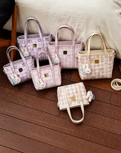 Detailed view of quilted plaid bucket bags with cute plush bunny charms in soft pastel tones