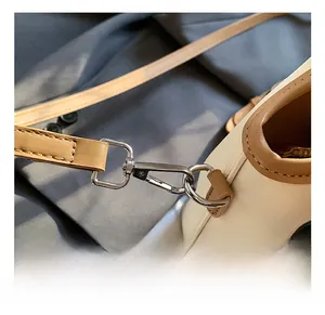 Macro shot of silver zinc alloy hook and light brown leather strap on cream bucket bag