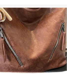 Close-up of vintage brown leather bag showing texture and dual metal zipper detail