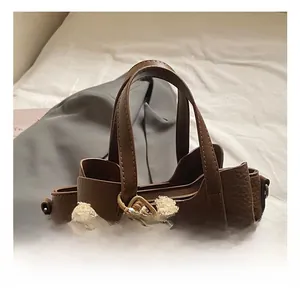 Detail of dark brown pebble leather tote bag with a soft white plush bear charm accessory