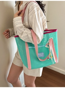 Détail du sac cabas en maille verte avec anses roses et breloques colorées